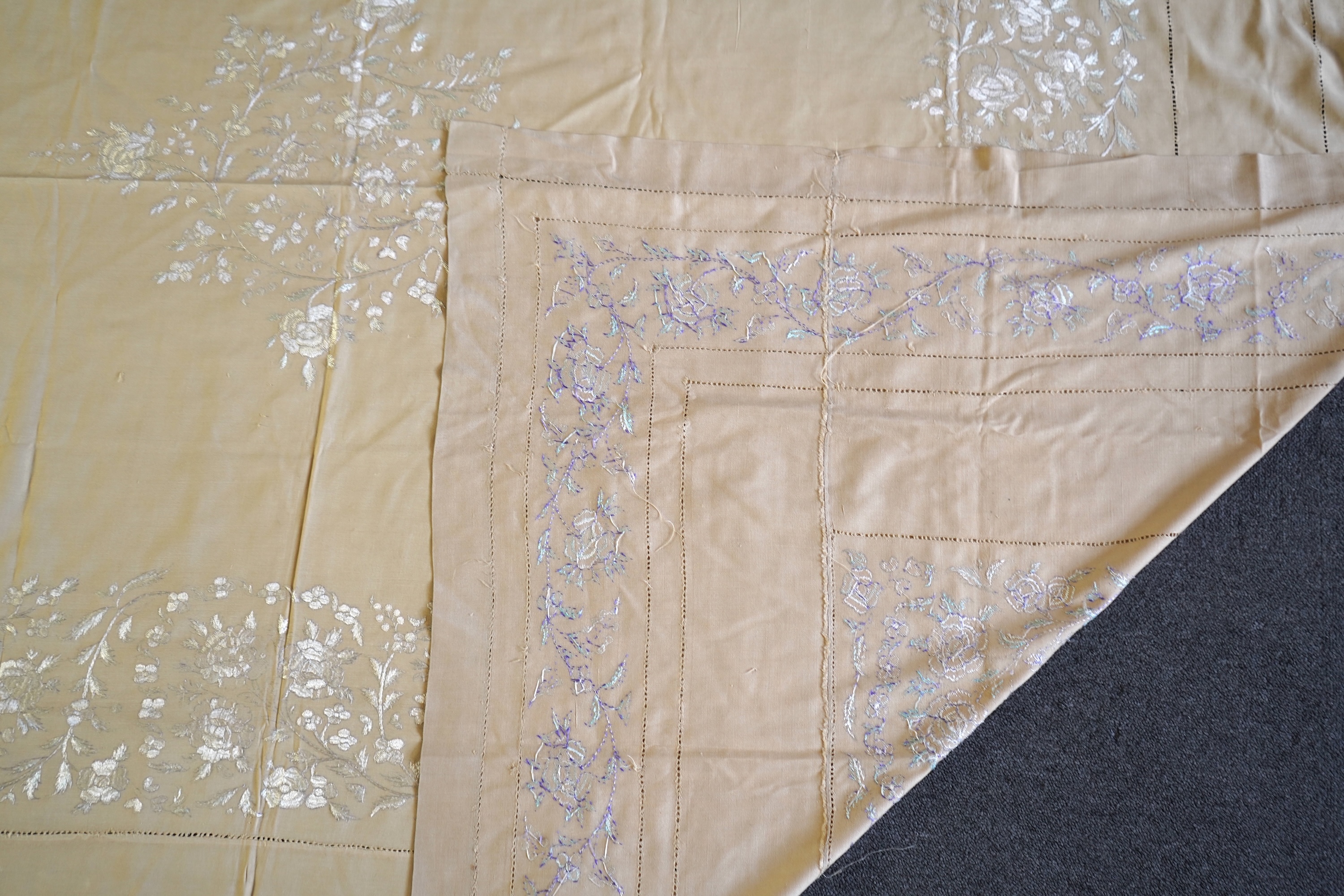 A 1920’s heavy shantung silk hand embroidered table cover. Worked with decorative rows of button hole stitch. Embroidered with white, green and blue silk flowers. 240cm x 204cm. Condition - some fine holes near corners,